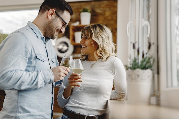 Szczęśliwa para patrząca na siebie podczas tostowania winem w kuchni
