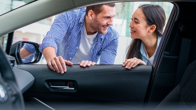Bezpłatne zdjęcie szczęśliwa para przy przedstawicielstwem handlowym samochodu