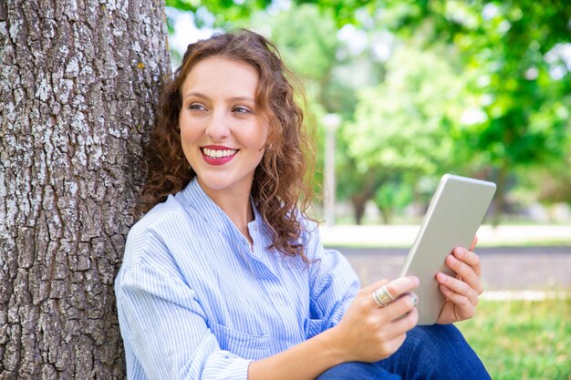 Szczęśliwa piękna kobieta używa mobilnego internet na pastylce