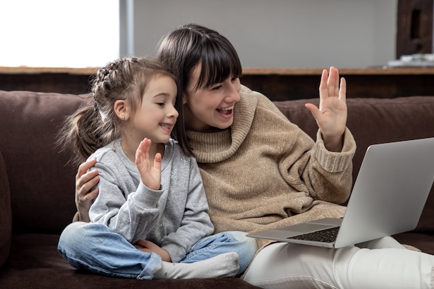 Szczęśliwa rodzina patrząc na ekran laptopa nawiązać rozmowę wideo na odległość. Uśmiechnięta matka i dziewczynka rozmawia z kamerą internetową na czacie internetowym.