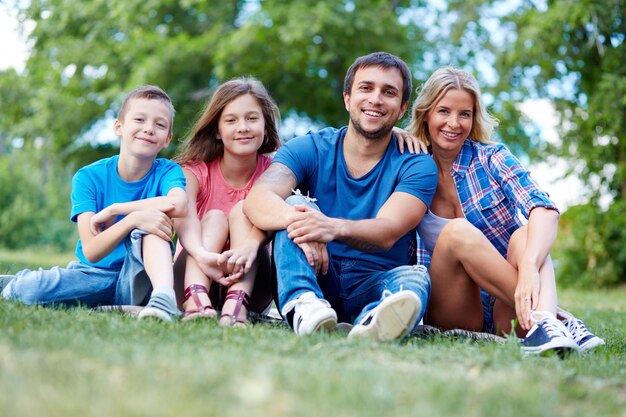 Szczęśliwa rodzina siedzi na trawie