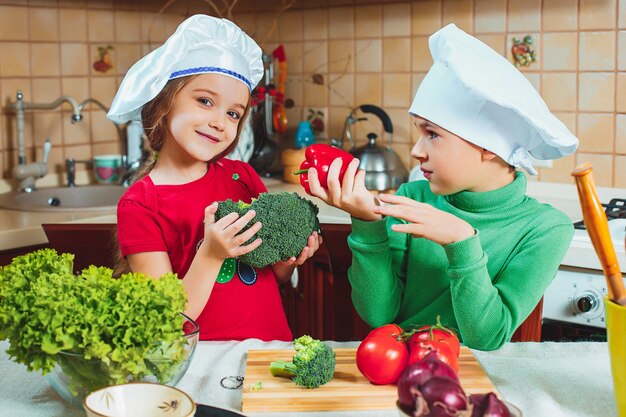 Szczęśliwa rodzina śmieszne dzieci przygotowują sałatkę ze świeżych warzyw w kuchni