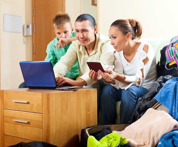 Bezpłatne zdjęcie szczęśliwa rodzina trzy rezerwuje hotel na internecie używać laptop