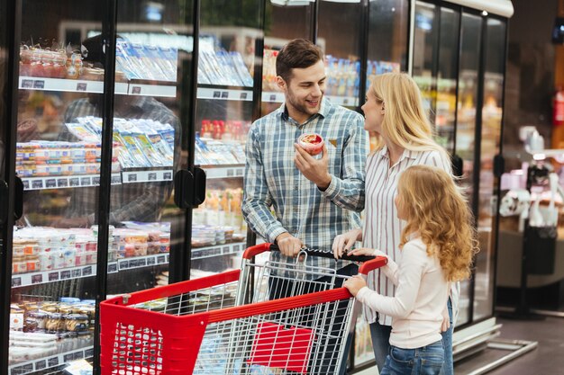 Szczęśliwa rodzina z wózek na zakupy w supermarkecie