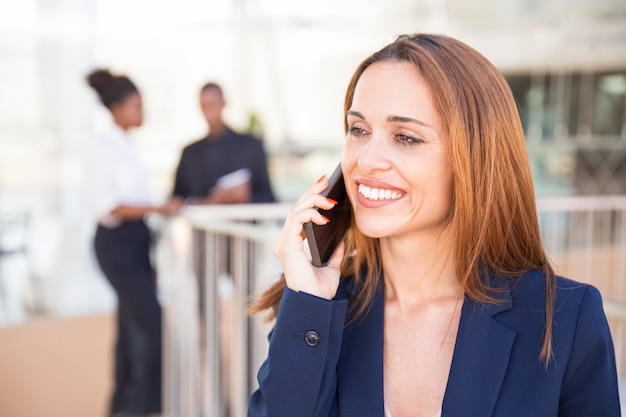 Szczęśliwa rozochocona biznesowa dama mówi na telefonie komórkowym