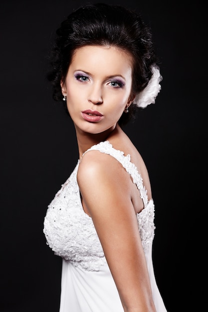 Szczęśliwa seksowna piękna panny młodej brunetki kobieta w białej ślubnej sukni z fryzurą i jaskrawym makijażem