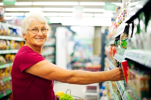 Szczęśliwa starsza kobieta w supermarkecie