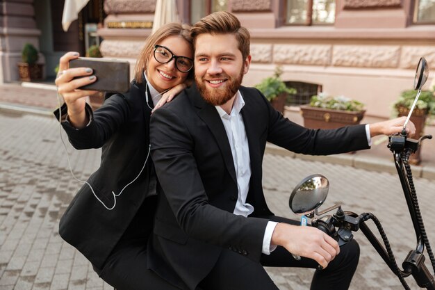 Szczęśliwa stylowa para siedzi na nowoczesnym motocyklu na zewnątrz