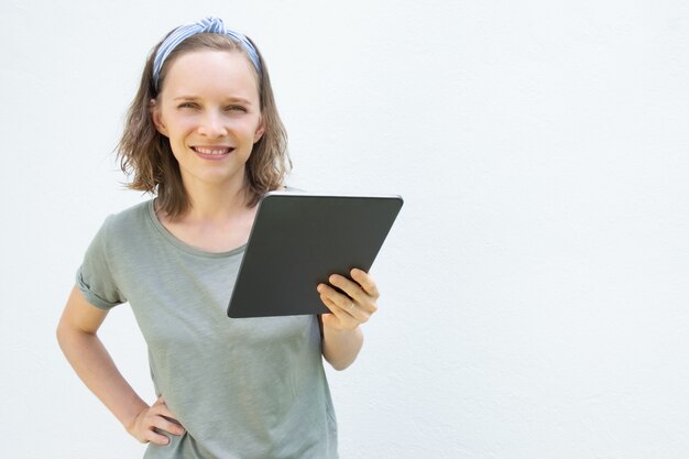 Szczęśliwa ufna młoda kobieta trzyma cyfrowego przyrząd