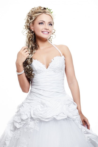 Szczęśliwa uśmiechnięta piękna panna młoda w białej sukni ślubnej z fryzurą i jasnym makijażem