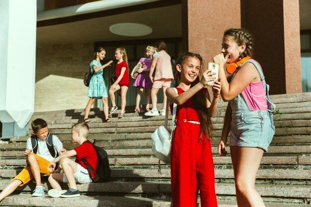 Szczęśliwe dzieci bawiące się na ulicy miasta w słoneczny letni dzień przed nowoczesnym budynkiem