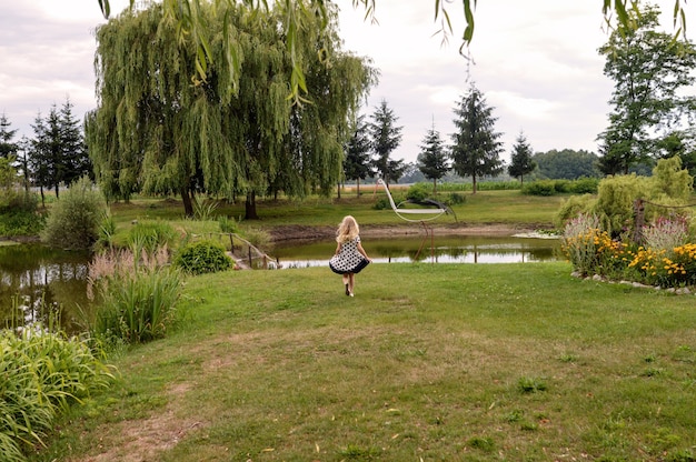 Szczęśliwe dziecko płci żeńskiej stojącej przed stawem w pięknym ogrodzie