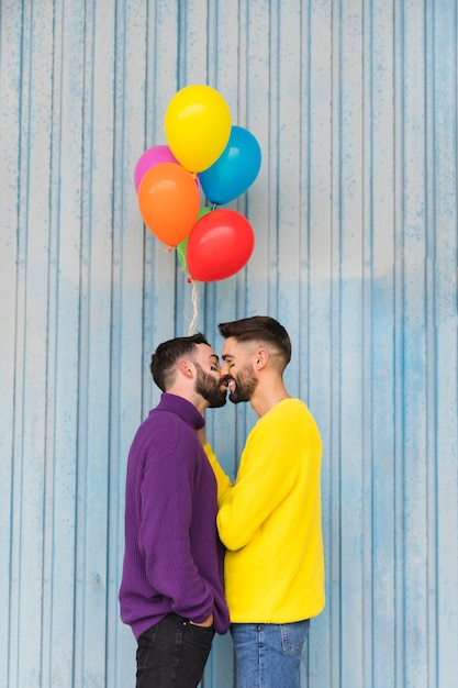 Szczęśliwe homoseksualne sympatie całuje i trzyma balony