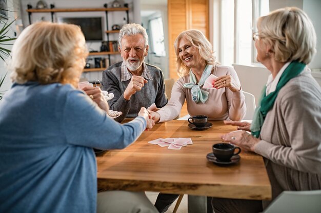 Szczęśliwe starsze kobiety ściskają dłonie po grze w karty z przyjaciółmi w domu