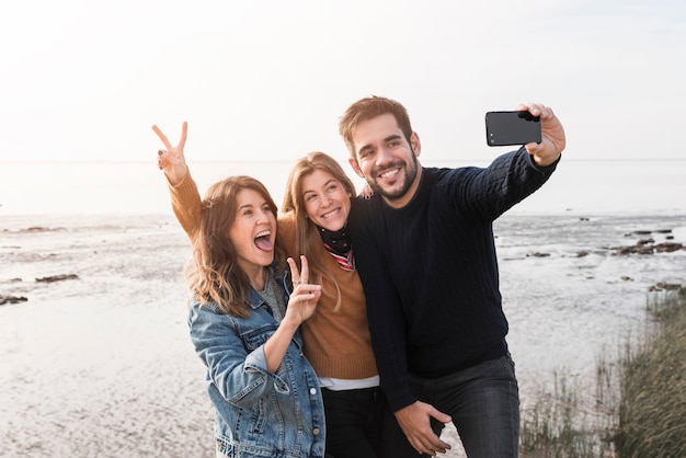 Szczęśliwi ludzie bierze selfie na seashore