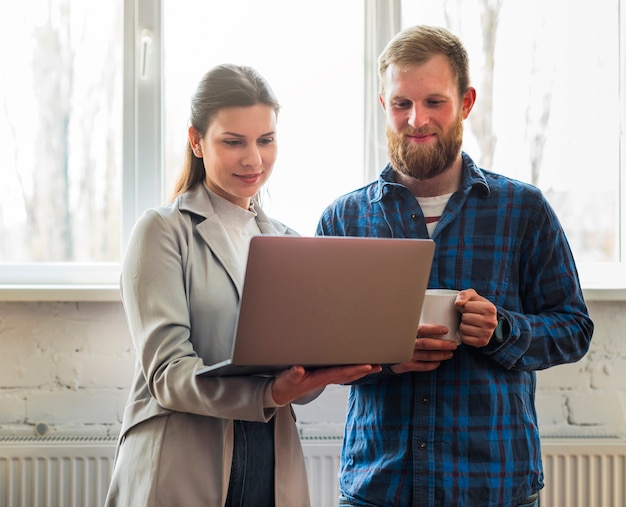 Szczęśliwi profesjonalni biznesmeni patrzeje laptop w biurze