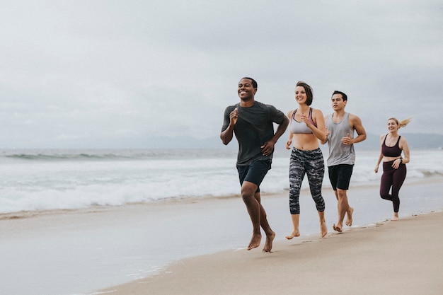 Szczęśliwi przyjaciele biegający razem na plaży