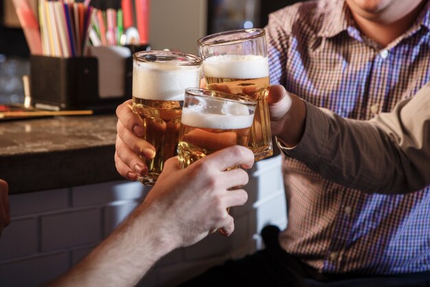 Szczęśliwi przyjaciele pije piwo przy kontuarem w pubie