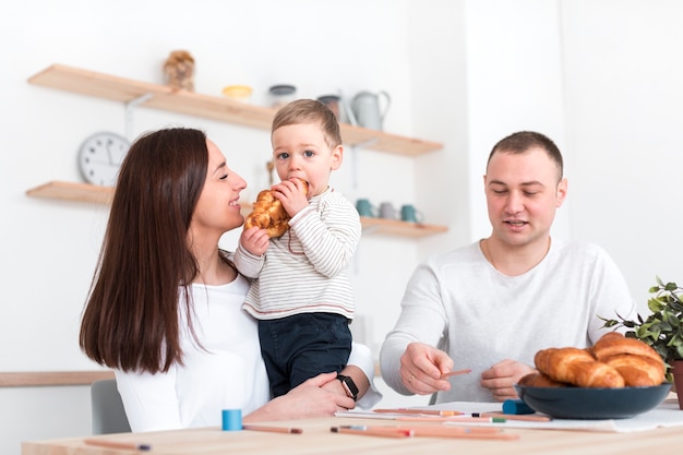 Szczęśliwi rodzice z dzieckiem przy kuchennym stołem