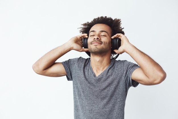 Szczęśliwy afrykański mężczyzna ono uśmiecha się słucha muzyka w hełmofonach.