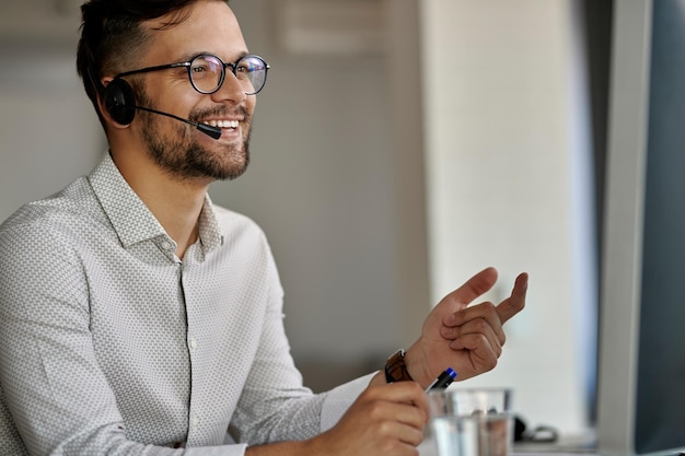 Bezpłatne zdjęcie szczęśliwy agent call center korzystający z komputera podczas komunikacji z klientami i pracy w biurze