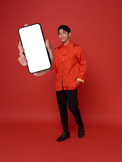 Bezpłatne zdjęcie szczęśliwy azjat w tradycyjnej sukience pokazujący pusty ekran telefonu komórkowego
