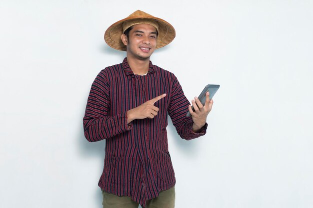 Szczęśliwy azjatycki rolnik używający smartfona na białym tle