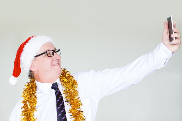 Szczęśliwy biznesmen w Santa kapeluszu bierze selfie