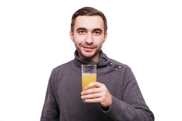 Szczęśliwy brodaty mężczyzna trzymający szklankę soku pomarańczowego i pokazujący kciuk w górę gest odizolowany na białej ścianie