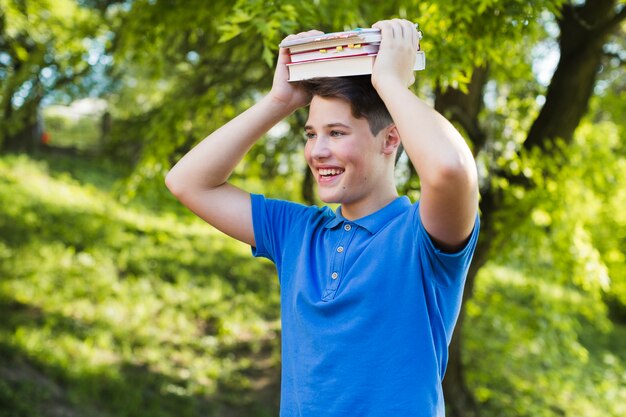 Szczęśliwy chłopiec nastolatek z książkami na głowie