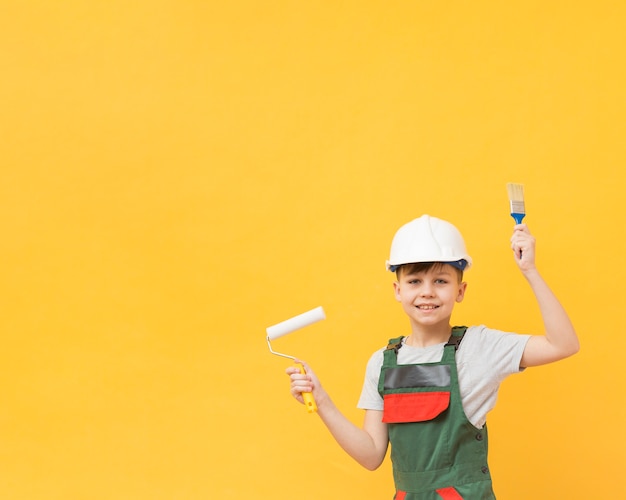 Bezpłatne zdjęcie szczęśliwy chłopiec trzyma narzędzia do malowania