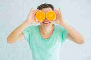 Bezpłatne zdjęcie szczęśliwy człowiek posiadający połowę dojrzałych pomarańczy przed jego oczami