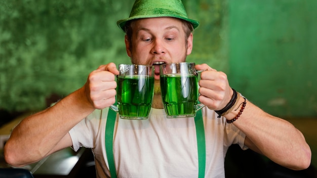 Bezpłatne zdjęcie szczęśliwy człowiek świętuje św. patrick's day z drinkami w barze