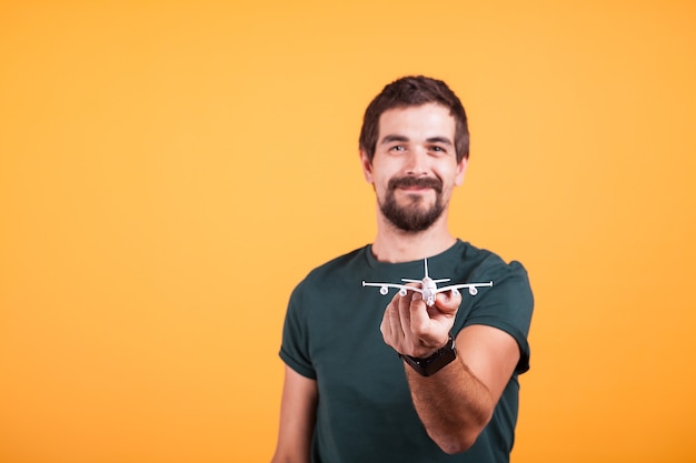 Bezpłatne zdjęcie szczęśliwy człowiek uśmiechający się pokazując samolot zabawka do kamery w obrazie koncepcji podróży. turystyka i wolność