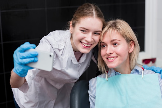 Szczęśliwy dentysta bierze selfie z pacjentem