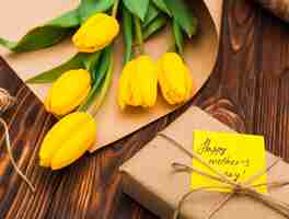 Bezpłatne zdjęcie szczęśliwy dzień matki napis z żółtych tulipanów i prezent