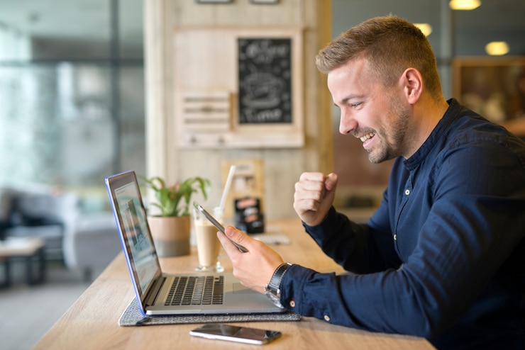 Bezpłatny plik Zdjęcie szczęśliwy freelancer z tabletem i laptopem w kawiarni