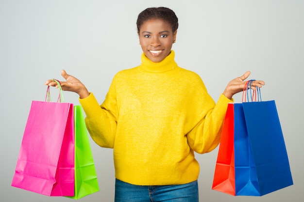 Szczęśliwy klient trzyma kolorowych torba na zakupy i pokazuje