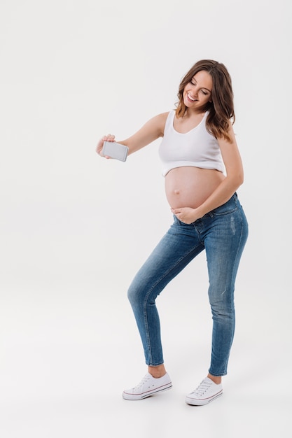 Szczęśliwy kobieta w ciąży robi selfie z jej brzuchem