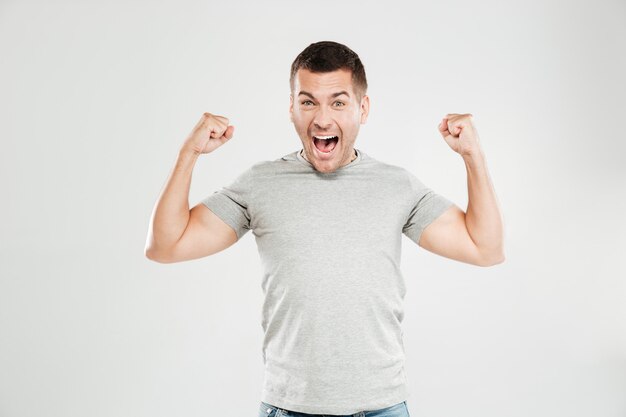 Szczęśliwy krzyczący mężczyzna pokazuje bicepsy.