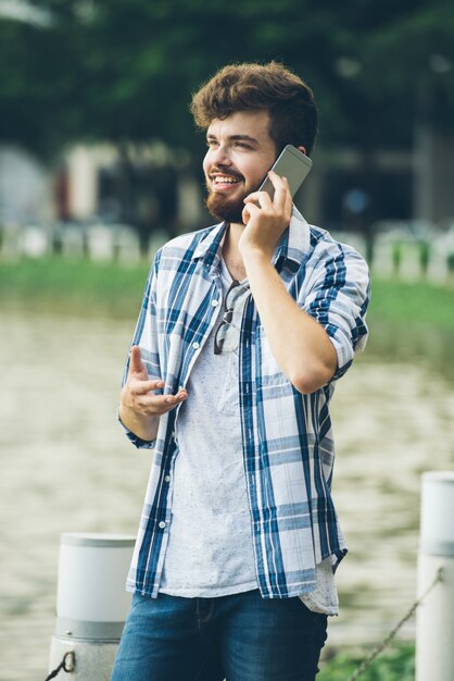 Szczęśliwy mężczyzna opowiada jego dziewczyna stoi outdoors na telefonie