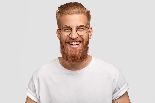 Szczęśliwy mężczyzna z długą, gęstą rudą brodą, ma przyjazny uśmiech