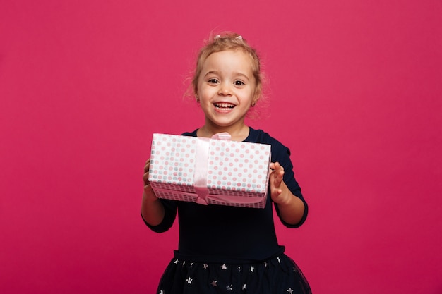 Bezpłatne zdjęcie szczęśliwy młodej dziewczyny mienia prezenta pudełko i patrzeć kamerę