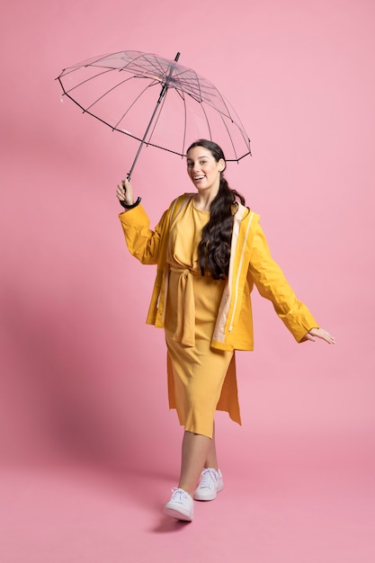 Szczęśliwy młodej kobiety odprowadzenie podczas gdy trzymający parasol