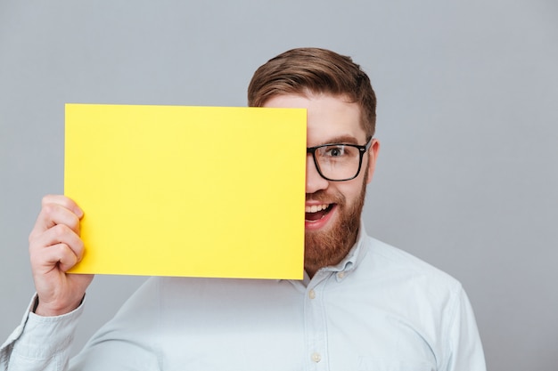 Szczęśliwy młody brodaty biznesmen trzyma pustego papier