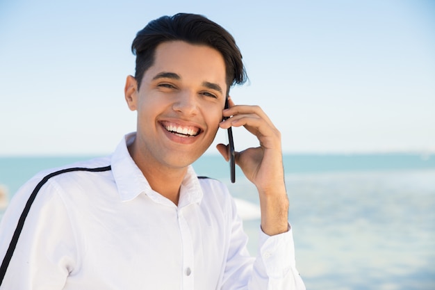 Szczęśliwy młody człowiek dzwoni na smartphone outdoors