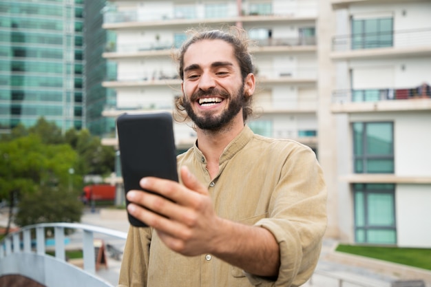 Szczęśliwy młody człowiek używa smartphone