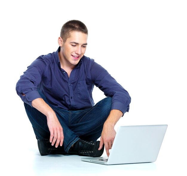Szczęśliwy młody człowiek z laptopem - na białym tle