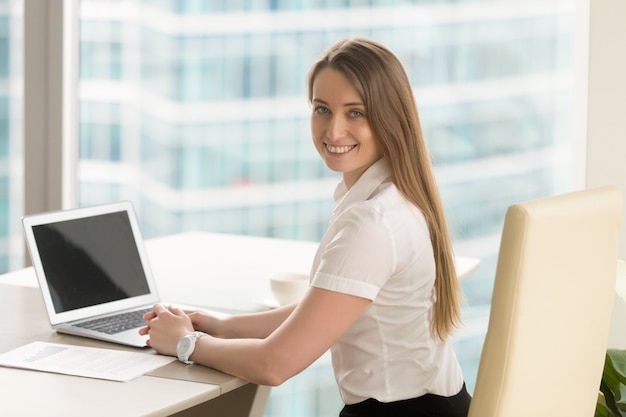 Szczęśliwy młody żeński przedsiębiorca pracuje przy biurem