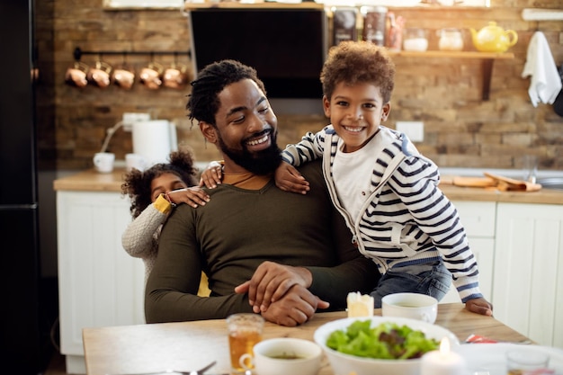 Szczęśliwy ojciec Afroamerykanów bawi się ze swoimi dziećmi w jadalni